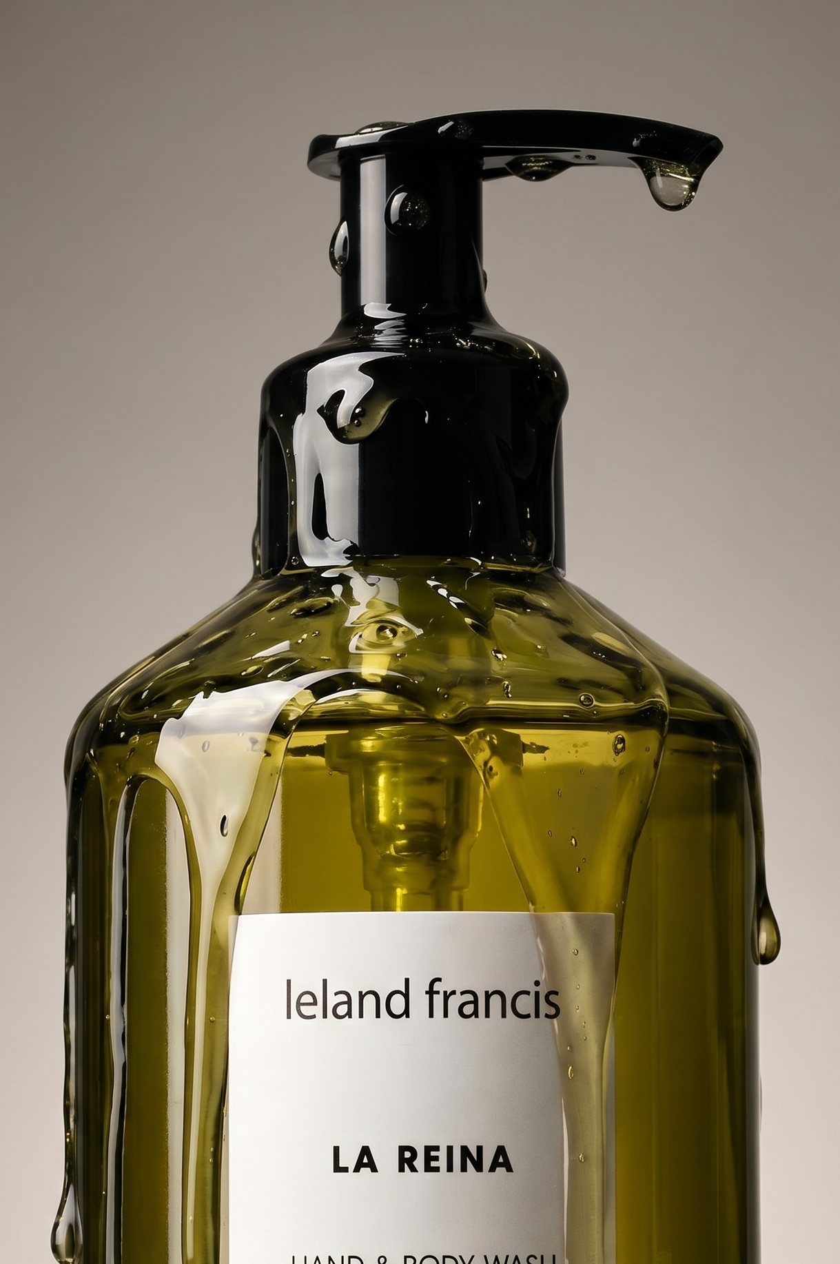green bottle of 'La Reina' hand and body wash by Ieland Francis on a gray background