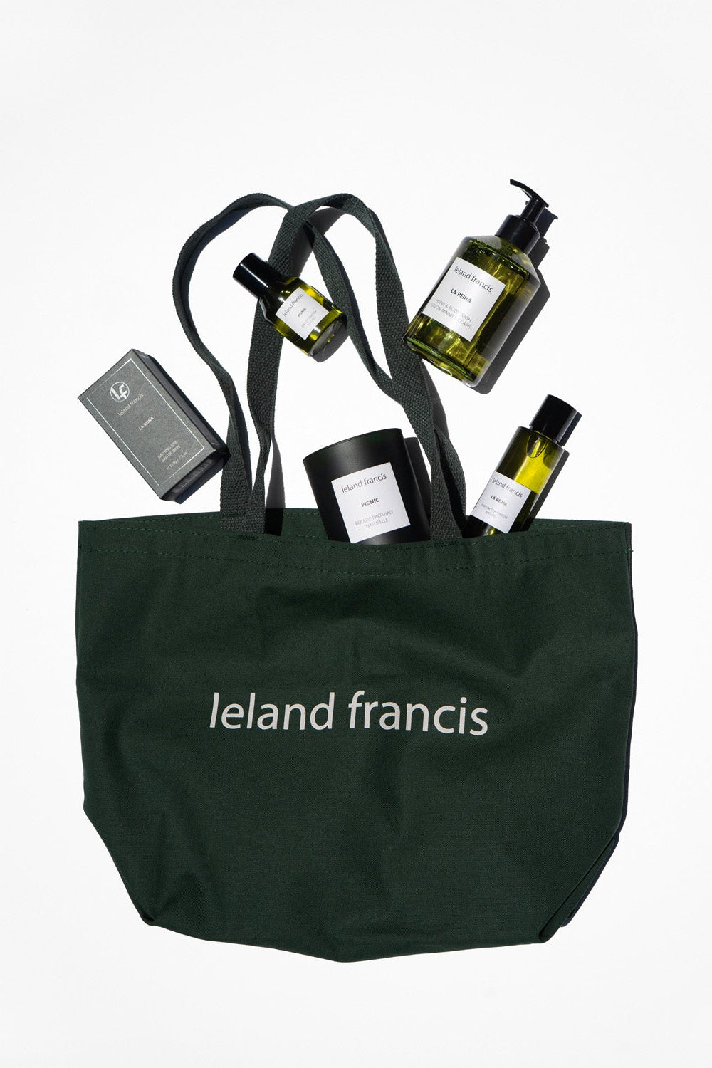 green tote bag with 'Ieland Francis' branding containing various products on a white background