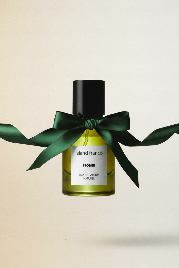 Perfume bottle with a green ribbon on a beige background
