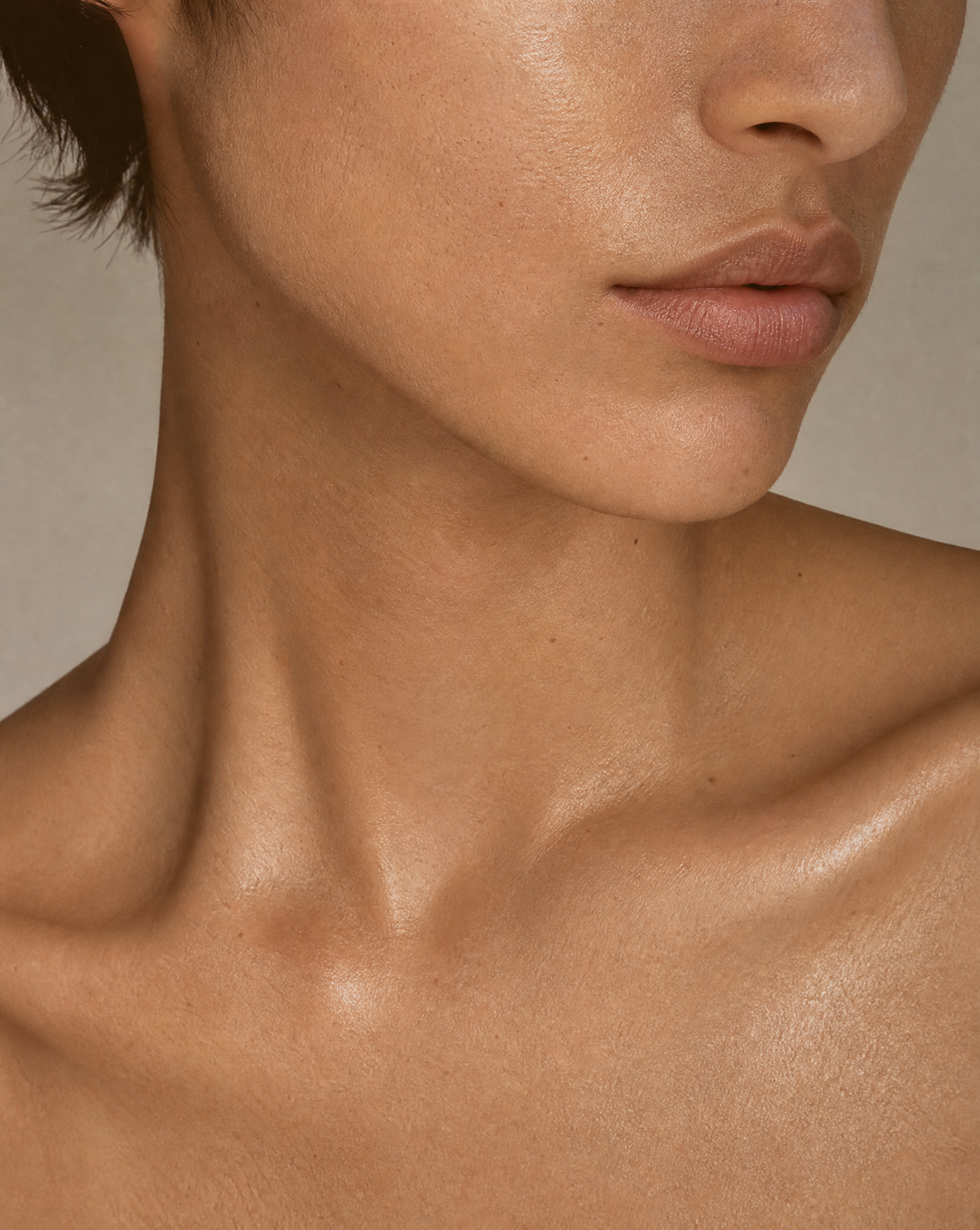 Close-up of a person's neck and shoulders with a neutral background