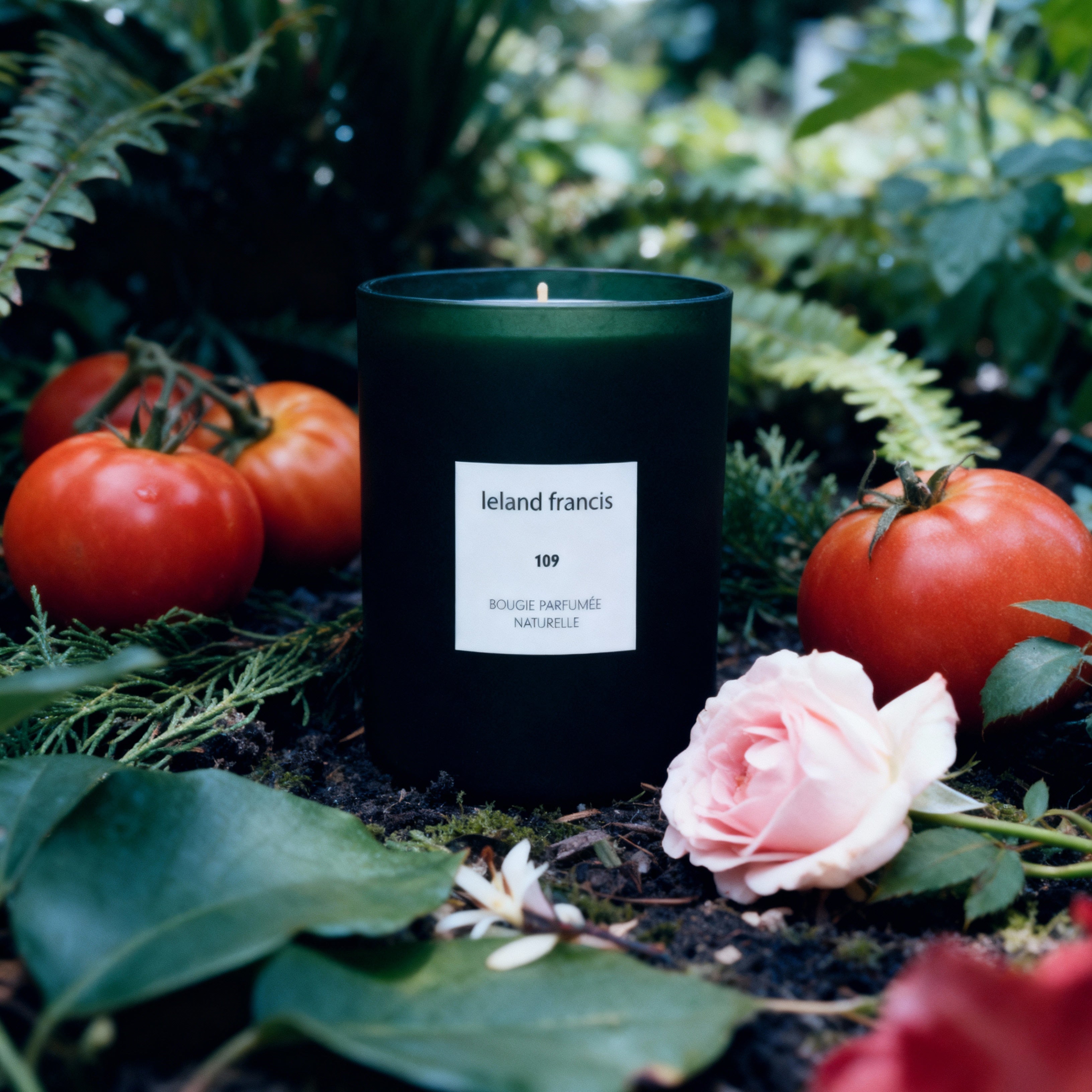Leland Francis candle in a garden setting with tomatoes and flowers