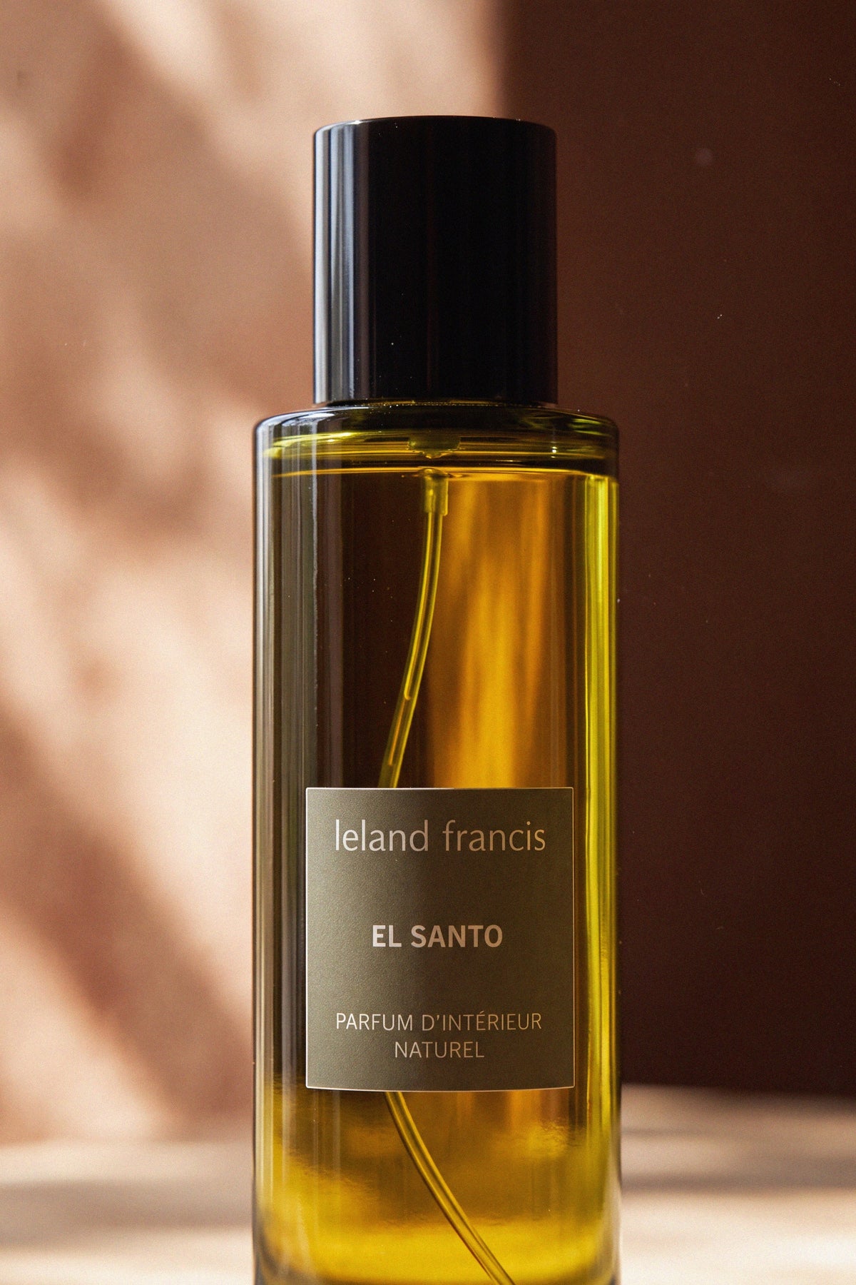 Close-up of the El Santo Room Spray bottle, black cap and leland francis label