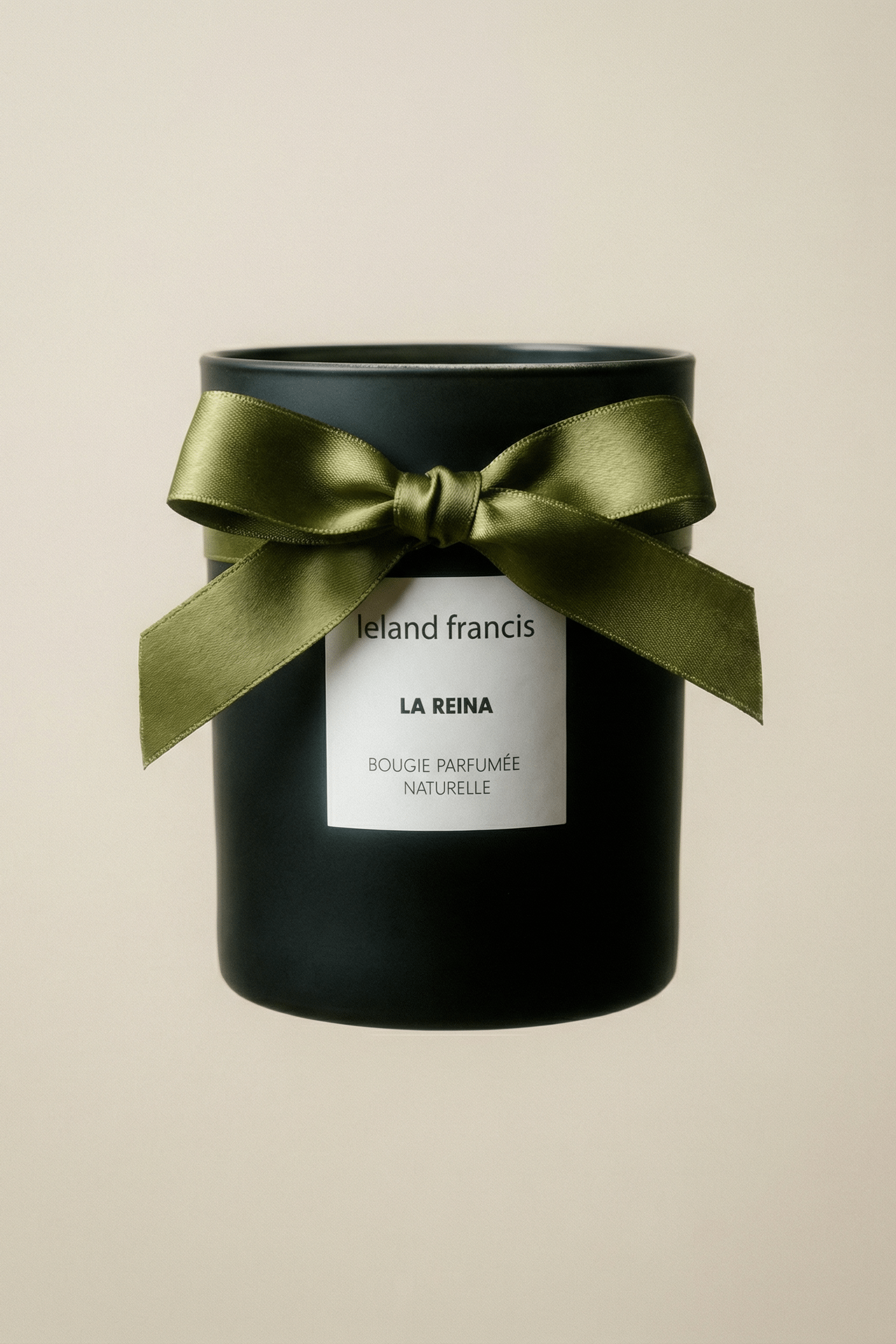 Black candle with a green ribbon and 'La Reina' label on a beige background