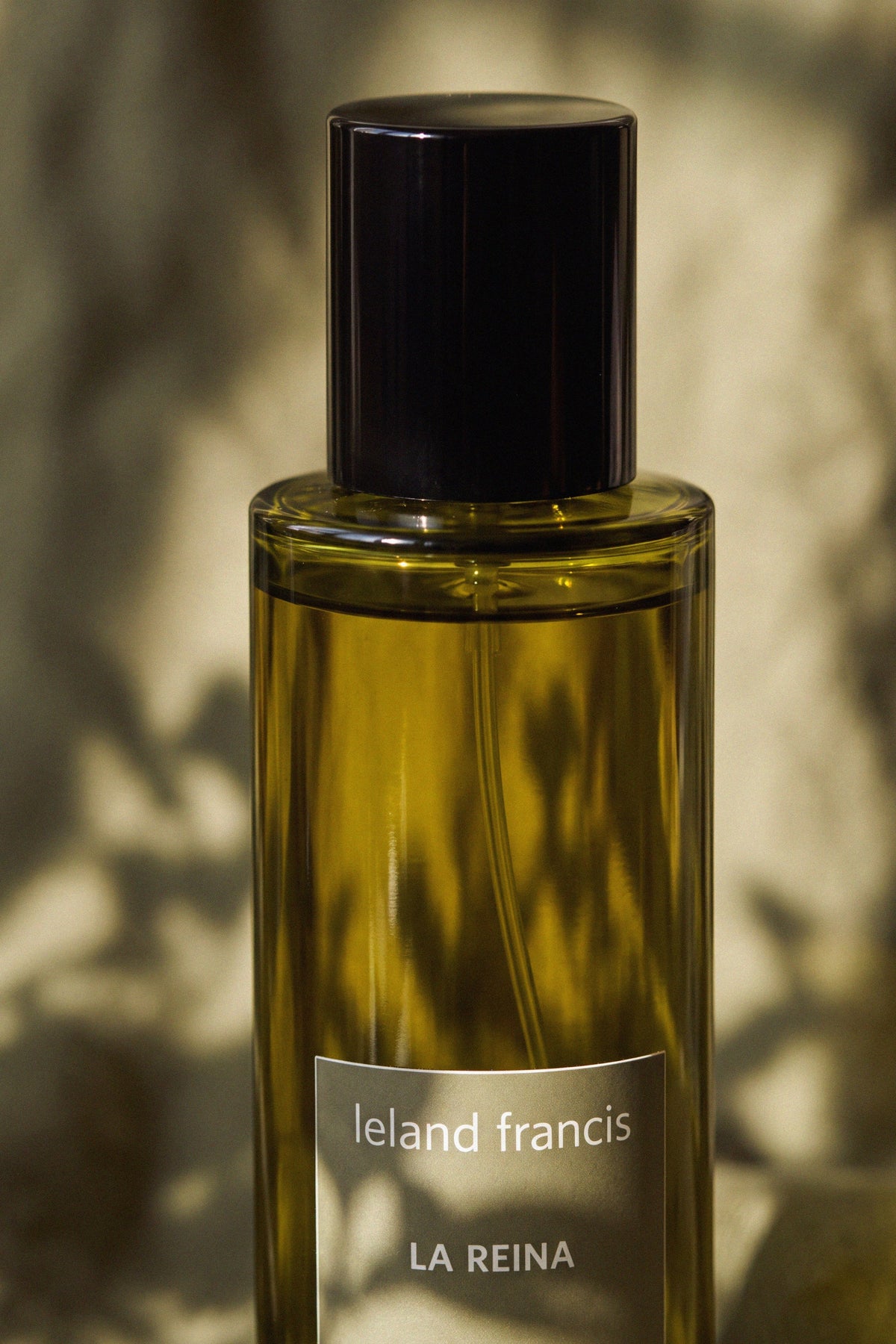 Close-up of the La Reina Room Spray bottle, black cap and leland francis label