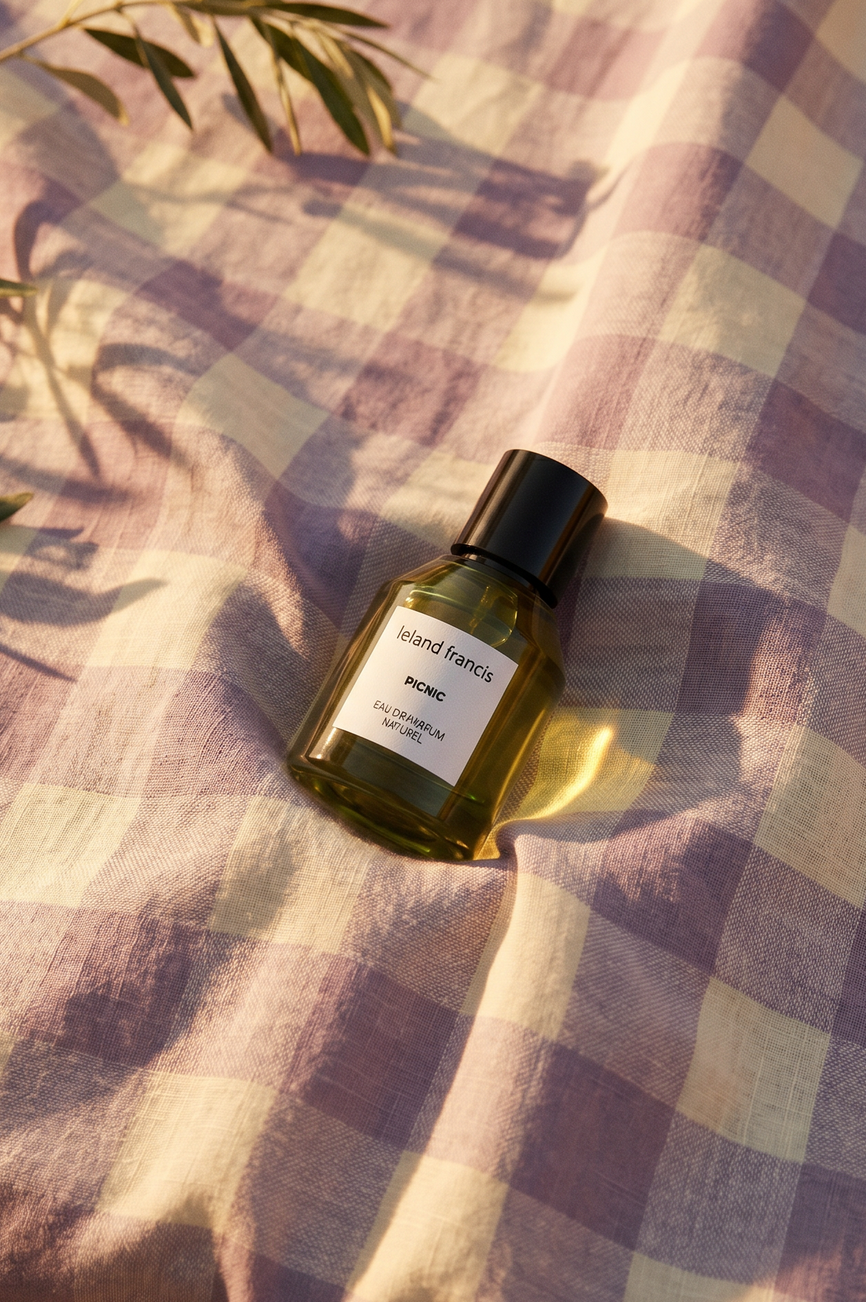 Perfume bottle on a checkered fabric with leaves